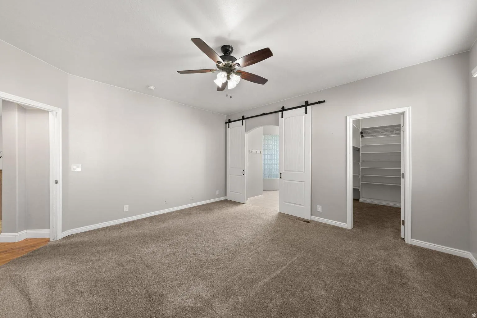 Spacious room featuring carpet flooring, a ceiling fan, and light gray wall paint