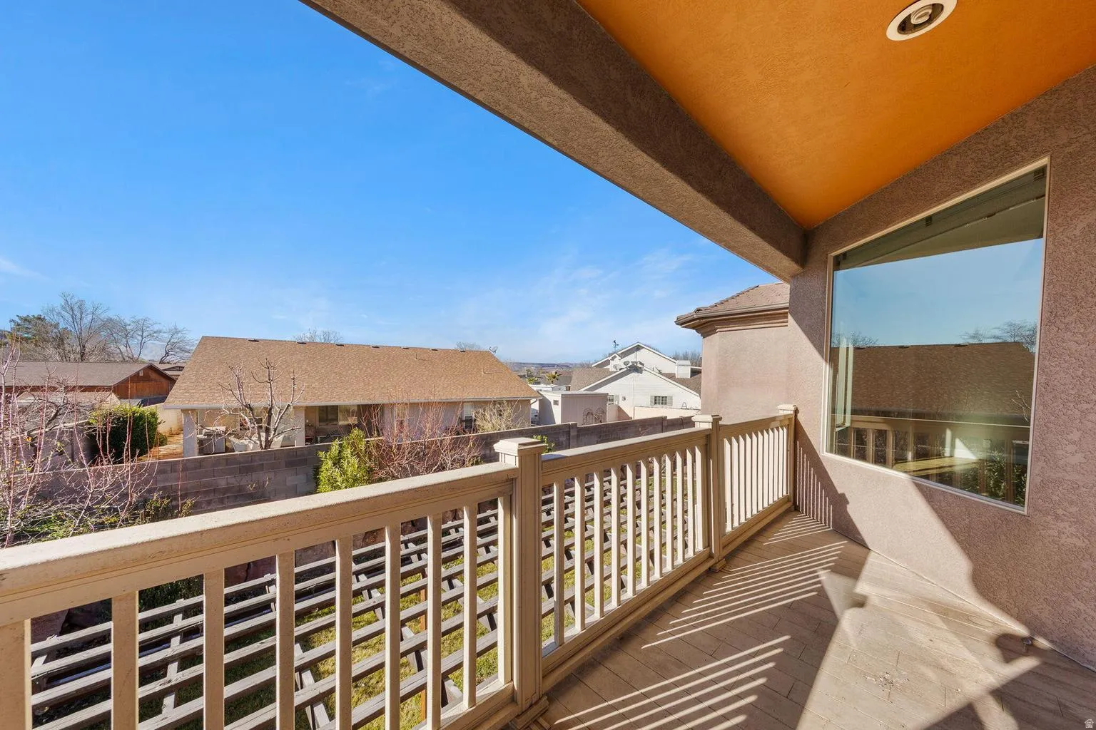 Upper-level balcony featuring a light-toned railing, a smooth stucco exterior, and an expansive window