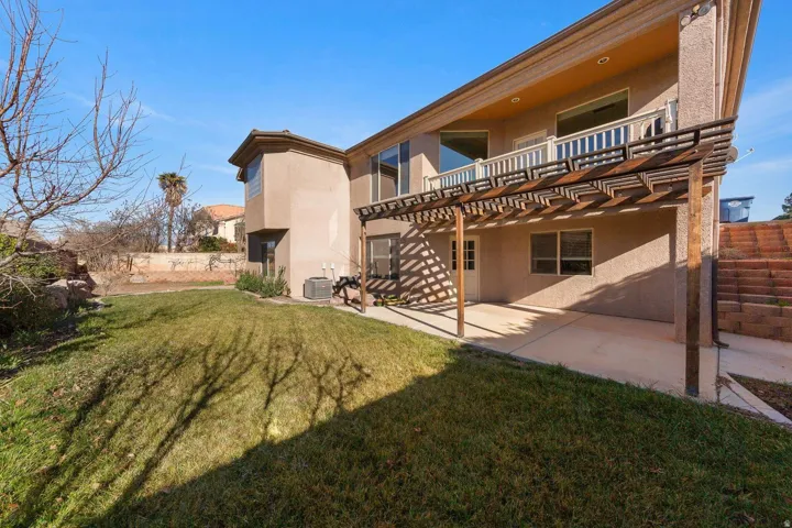 Rear exterior with an expansive concrete patio and wood pergola