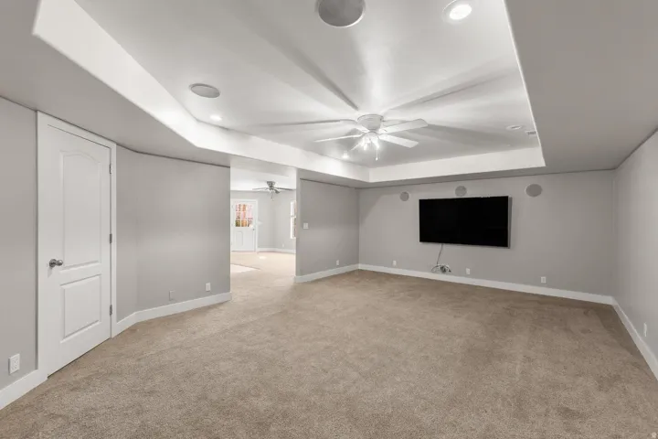Spacious interior room featuring a tray ceiling with recessed lighting and a ceiling fan