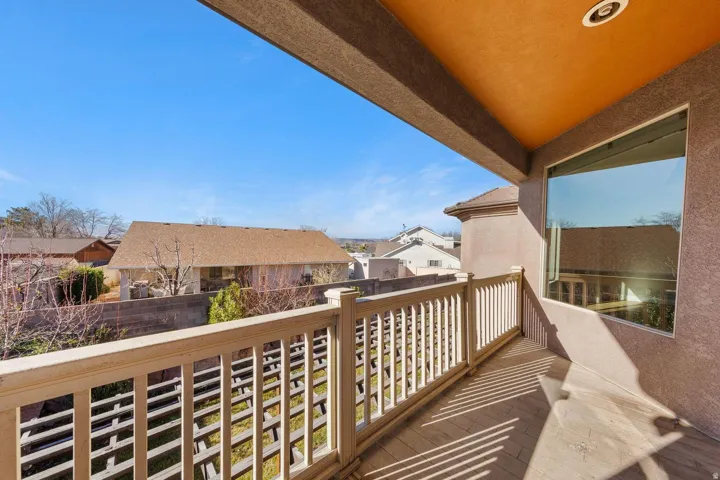 Upper-level balcony featuring a light-toned railing, a smooth stucco exterior, and an expansive window