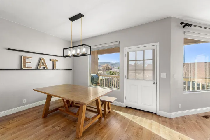 Dining area featuring wood-finish flooring, a contemporary linear chandelier, and light gray wall paint