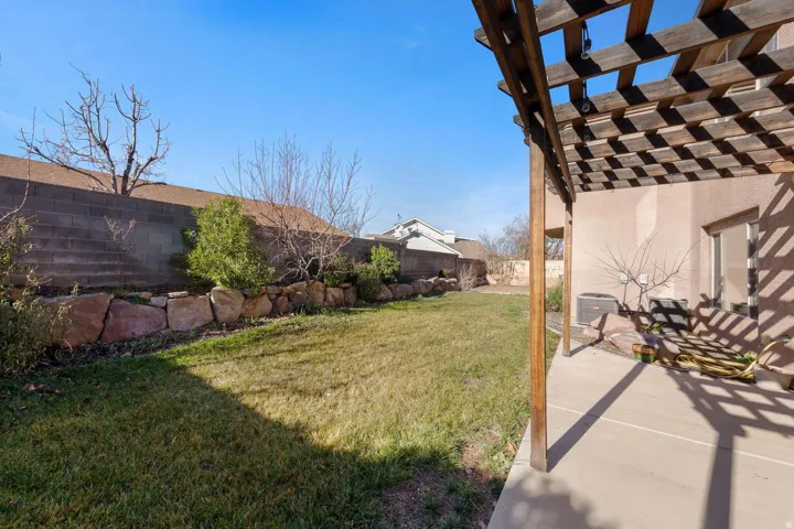 Concrete patio with a wooden pergola featuring string lighting