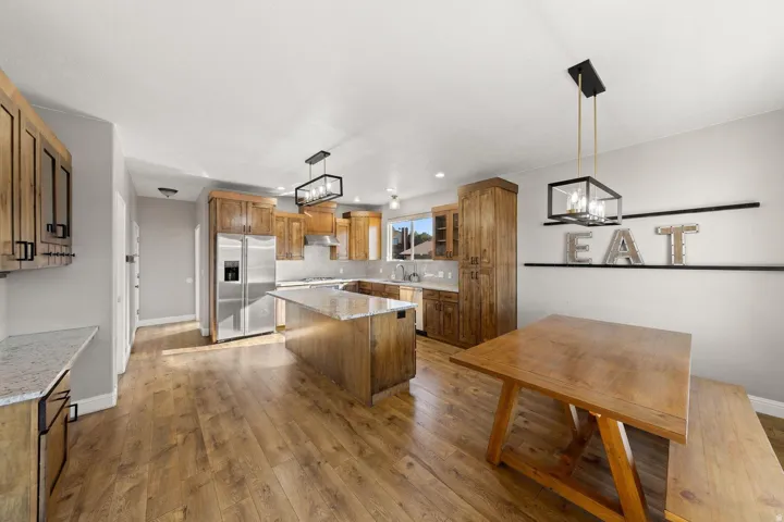 Spacious kitchen featuring wood-finish flooring, an island with countertop, and stainless steel appliances