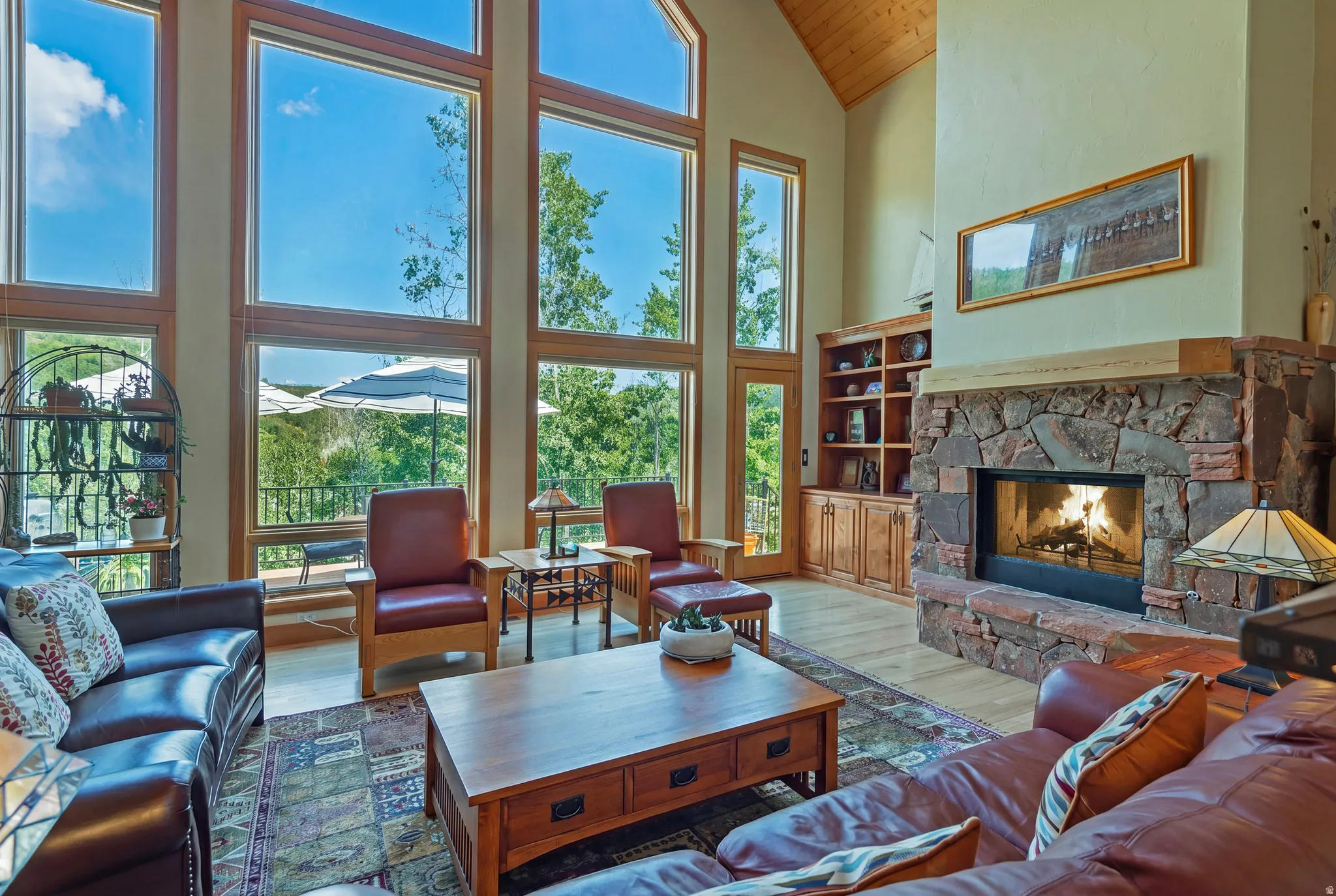 Spacious living area featuring a stone-clad fireplace with wood mantle, vaulted ceilings with wood-finish paneling, and wood-finish flooring
