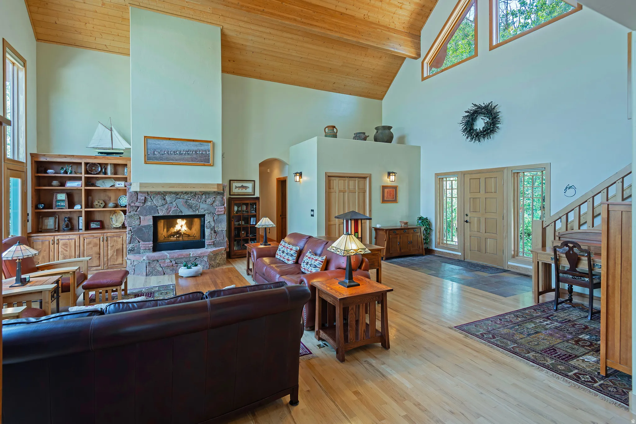 Vaulted wood-paneled ceilings over a spacious room featuring a stone fireplace