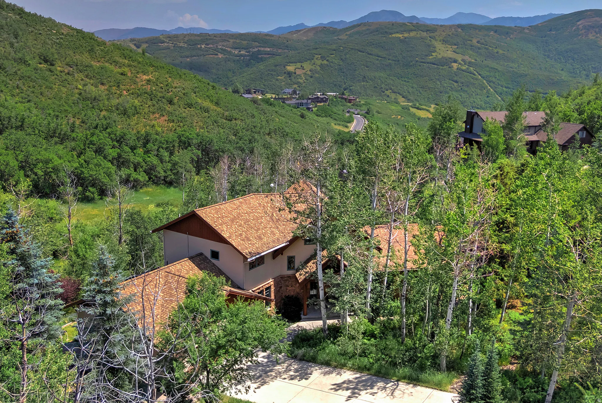 Expansive property featuring a multi-level residence with a shingle roof and a concrete driveway