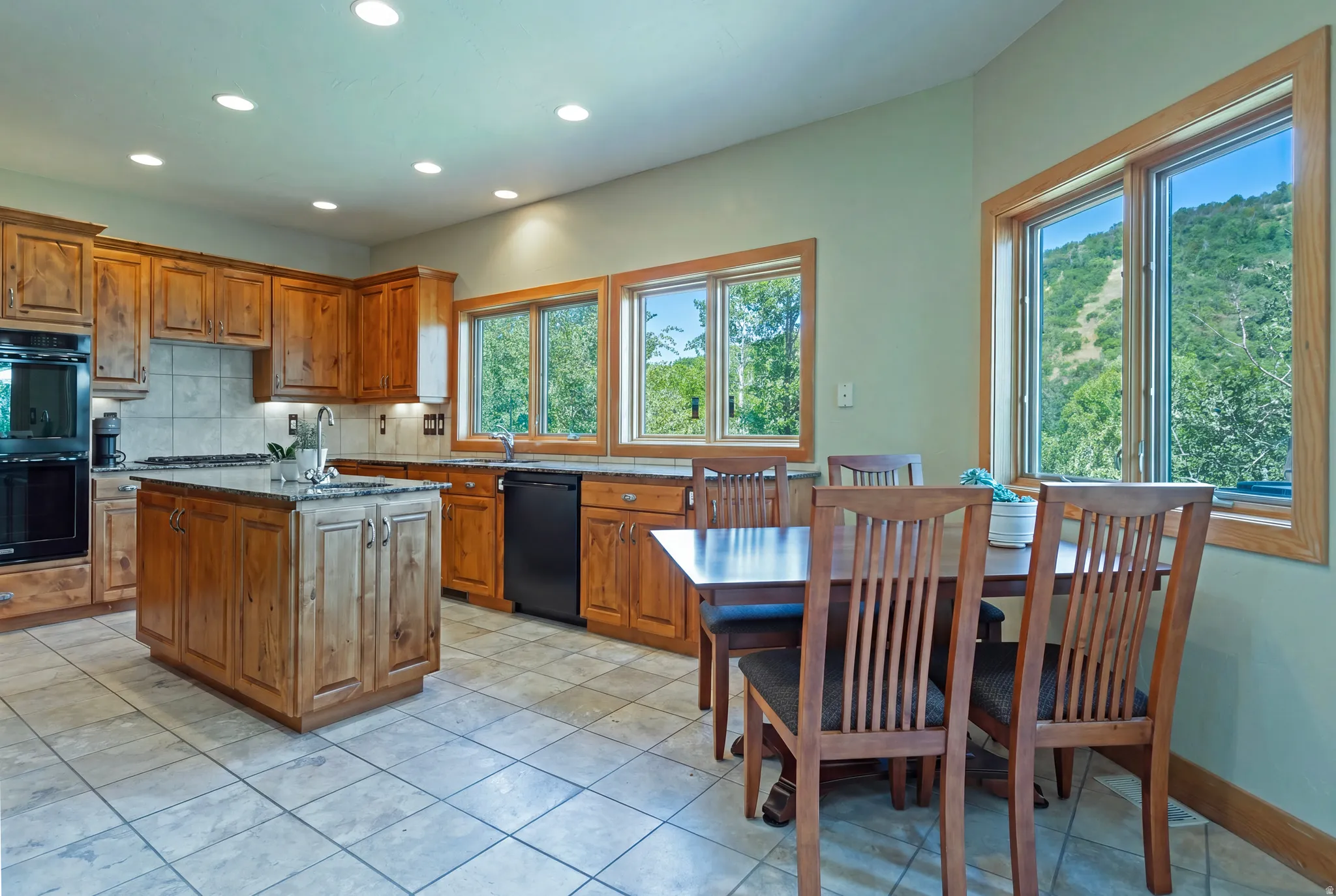 Kitchen featuring wood cabinetry, a central island with a sink, recessed lighting, and tile flooring