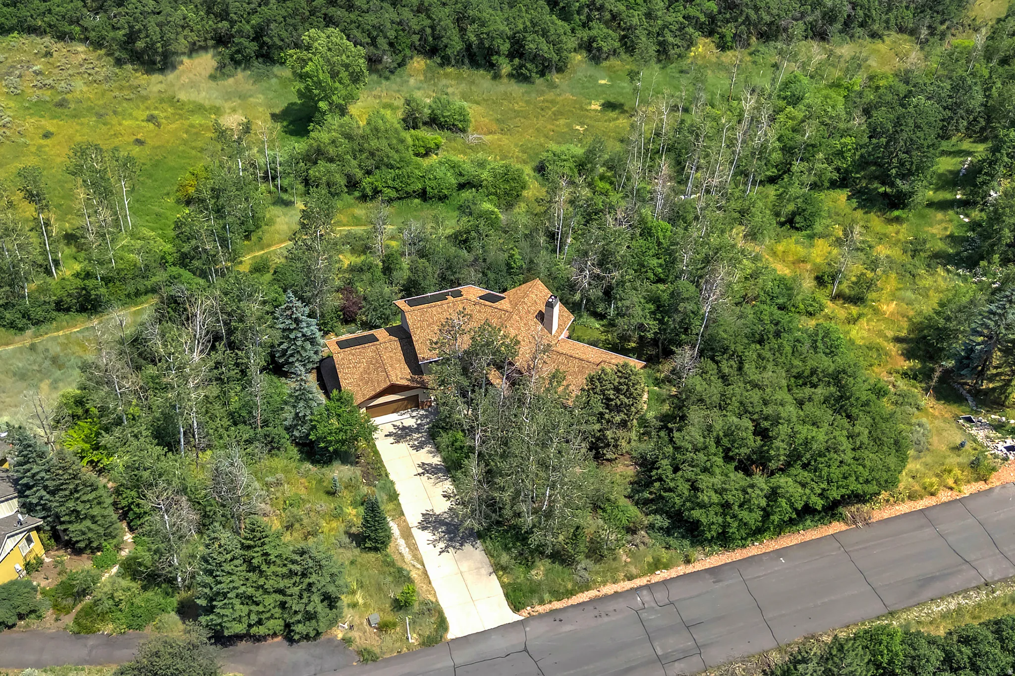 Elevated property with a multi-gabled roofline and attached garage, surrounded by mature trees
