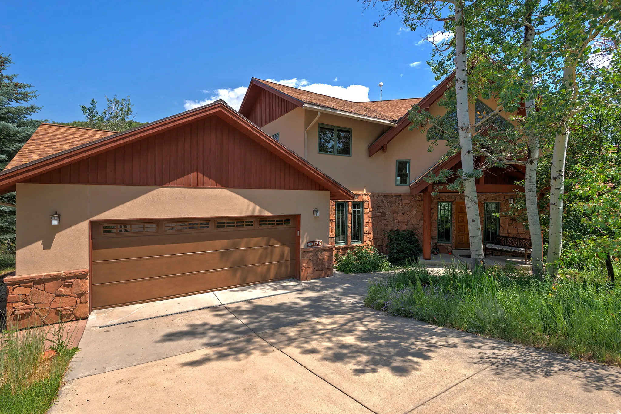 Stucco exterior featuring extensive stone detailing and wood accents