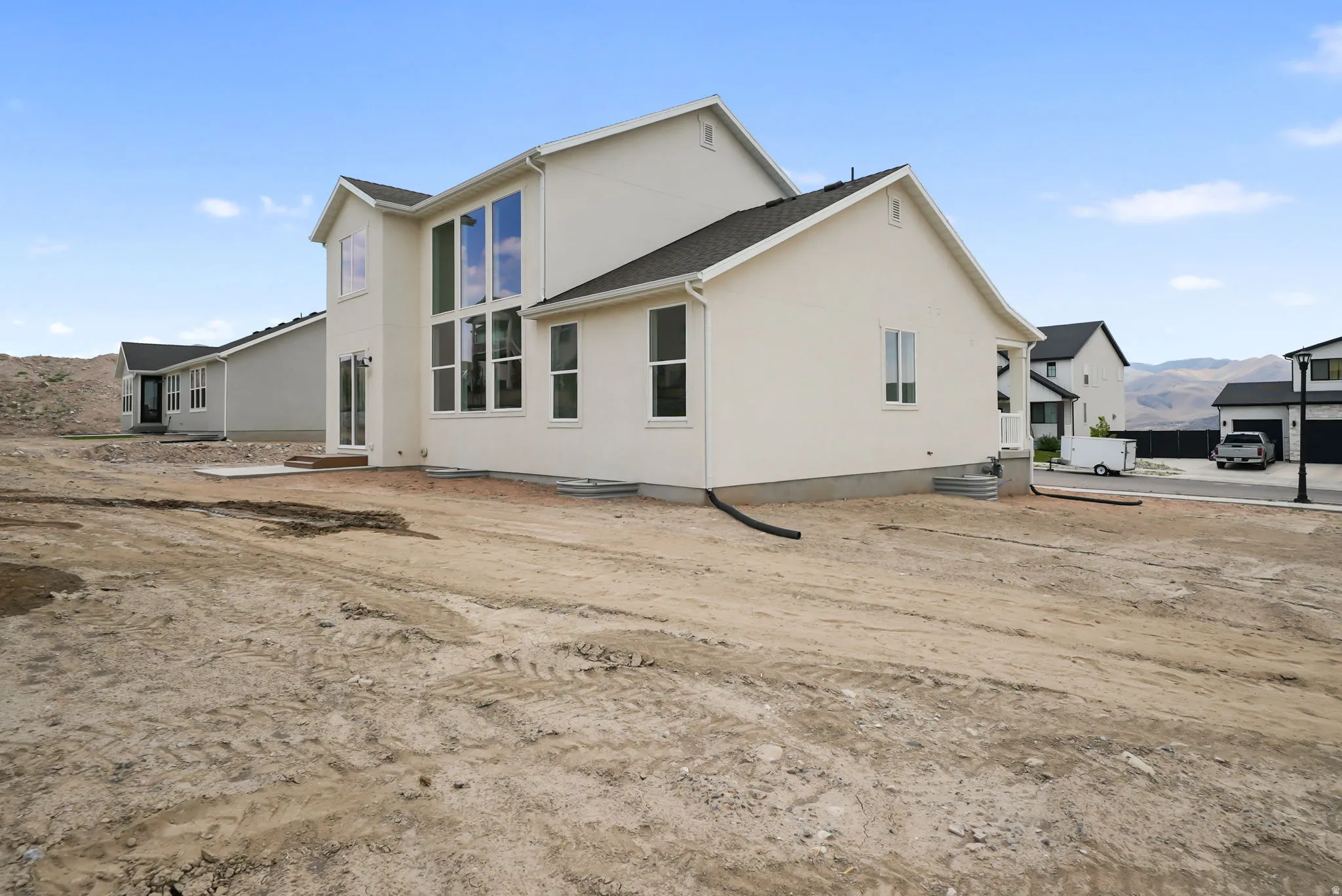 Contemporary stucco exterior with a multi-pane window wall, sliding glass door, and a dark shingle roof