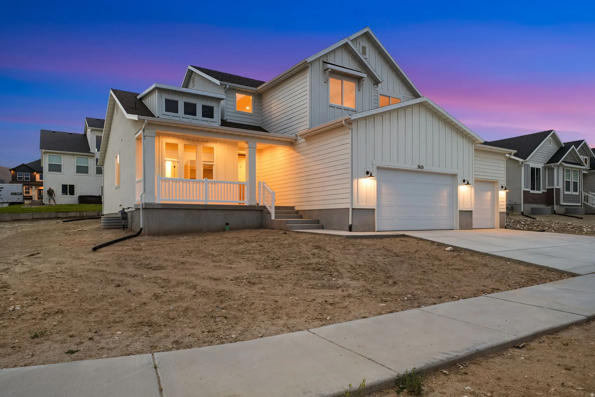 Contemporary home featuring white vertical and horizontal siding, a covered front porch with white railings, and a two-car garage with individual doors