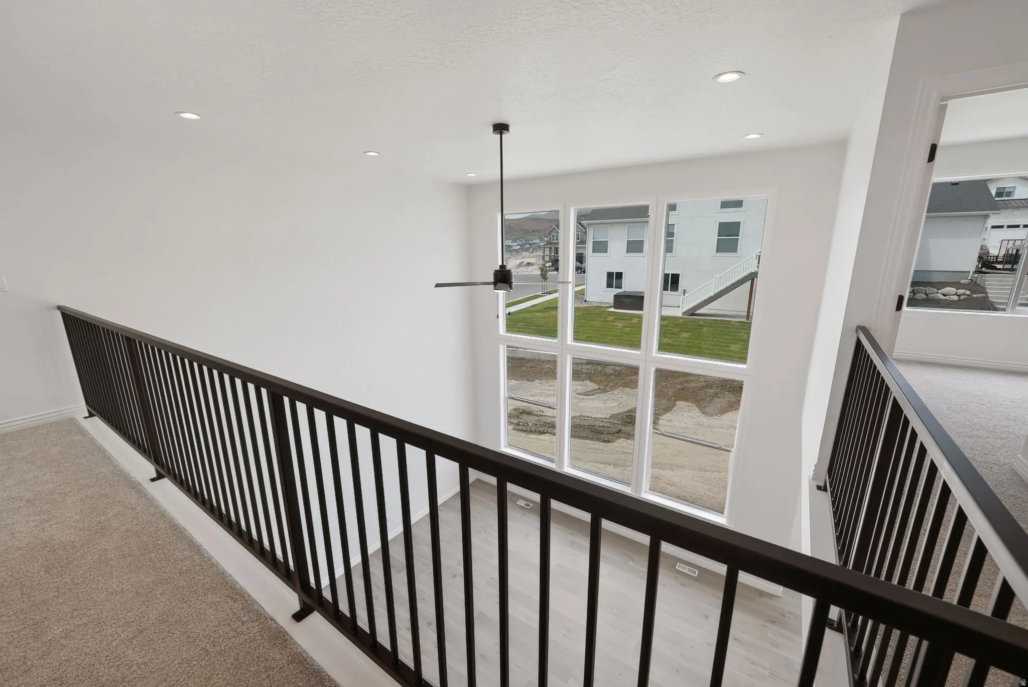 Two-story interior with a modern black spindle railing, recessed lighting, and a contemporary ceiling fan