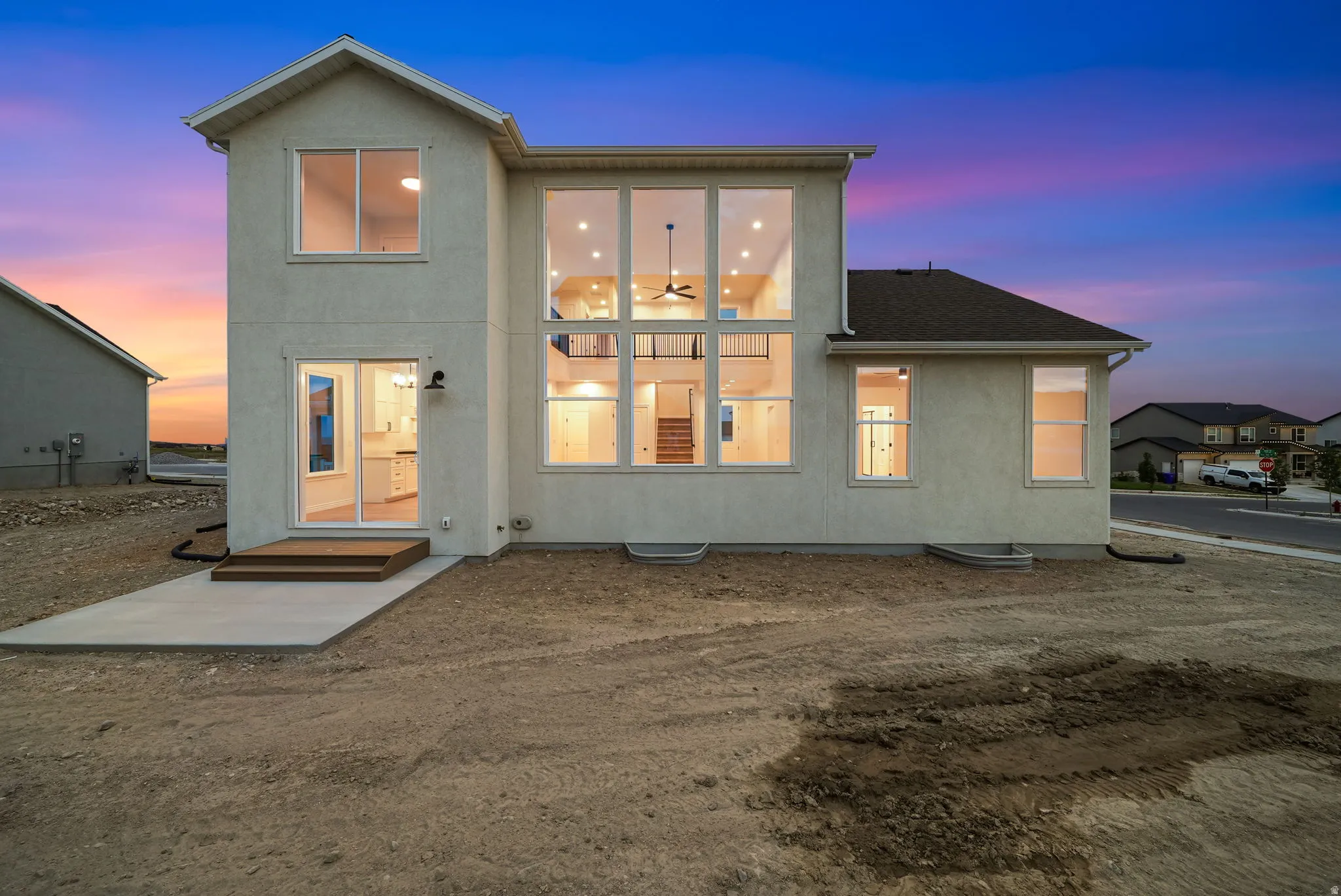 Rear exterior featuring a multi-story window wall, stucco finish, and a sliding glass door leading to an elevated landing