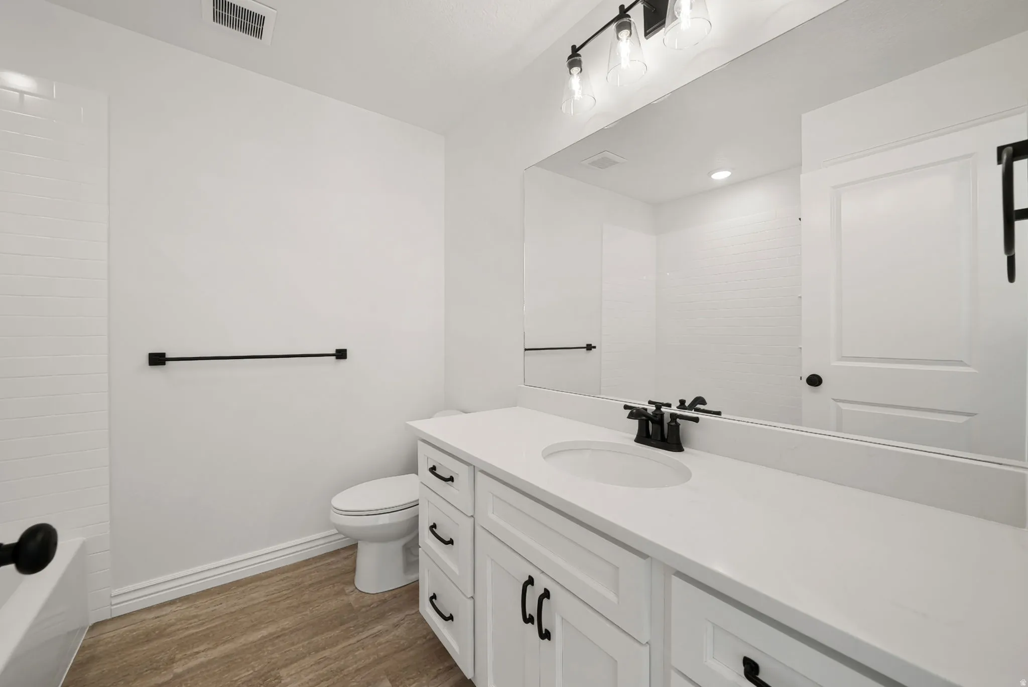 Contemporary bathroom featuring a white vanity with a solid surface countertop, an undermount sink, and black hardware
