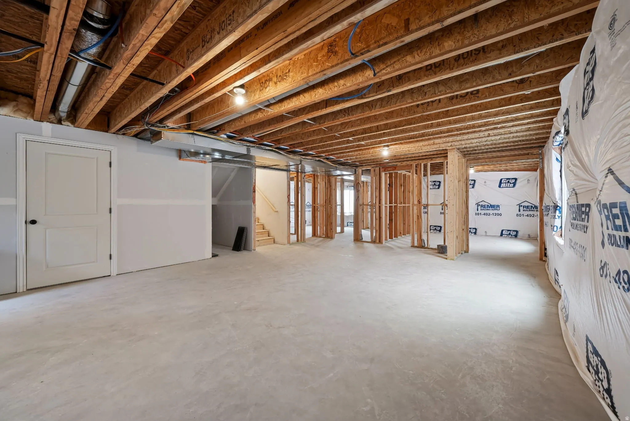 Unfinished basement featuring exposed wood joists, concrete flooring, framed interior walls, and partially finished drywall