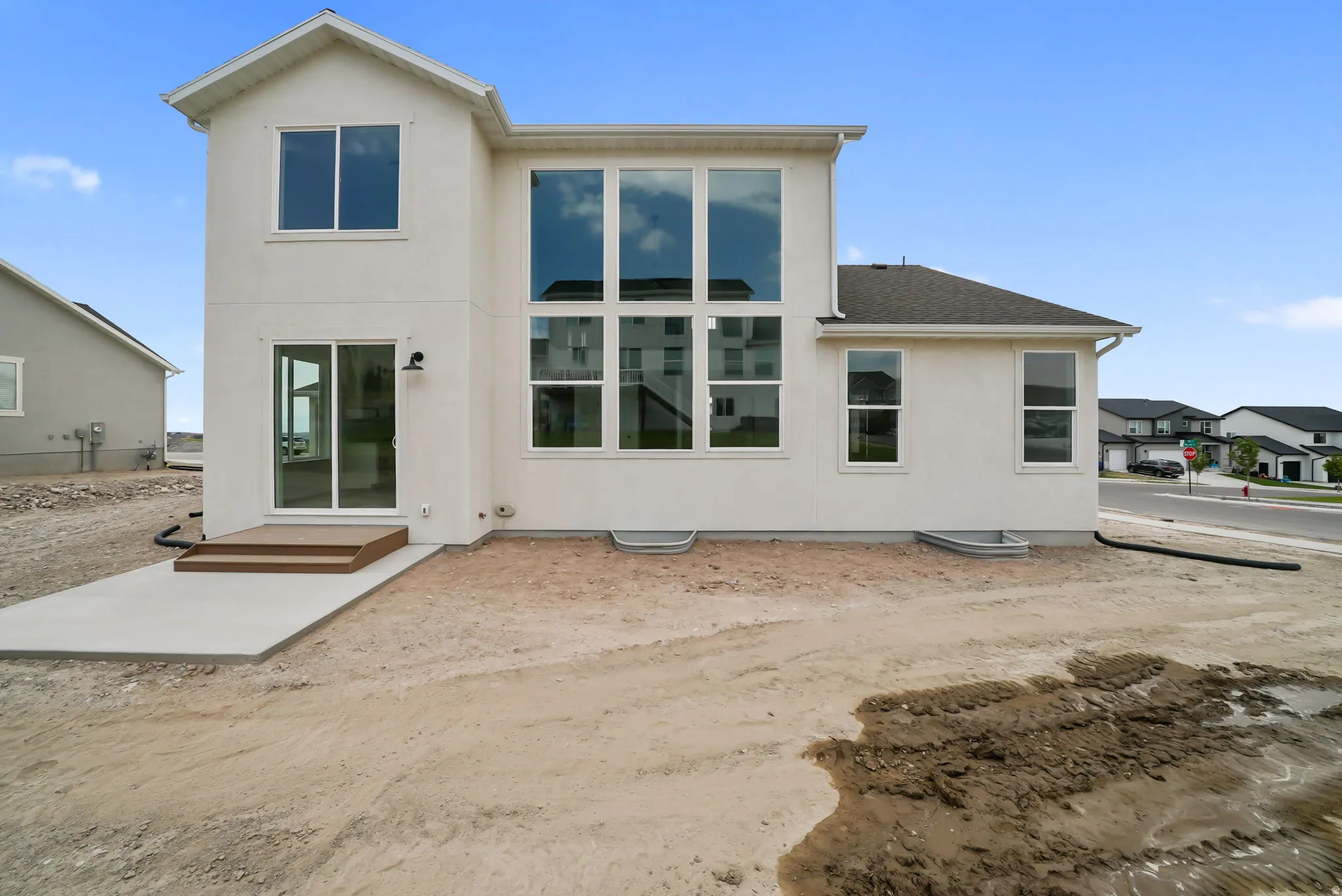 Rear exterior featuring a large two-story window array, white stucco finish, and a sliding glass door