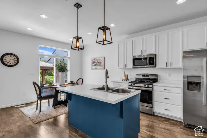 Kitchen featuring an island with dual sinks, white shaker cabinetry, stainless steel appliances, and recessed lighting