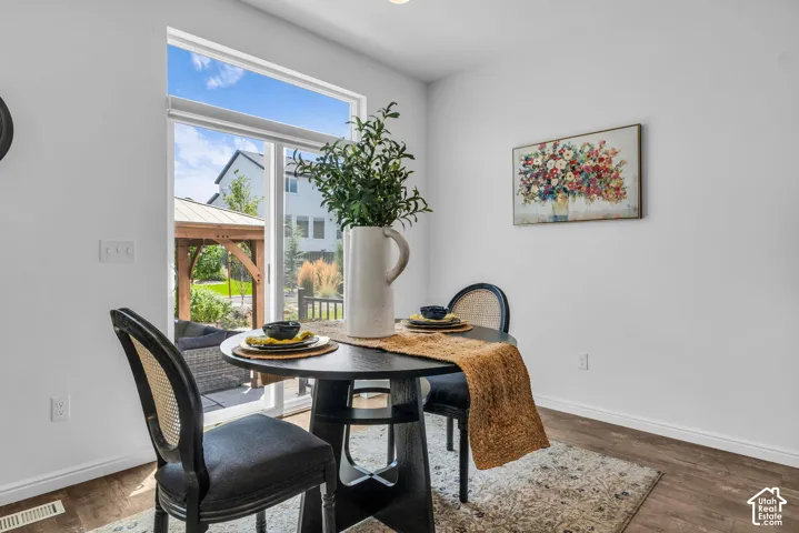 Dining area with wood-finish flooring and bright white walls