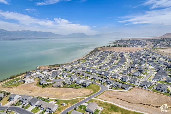 Expansive residential development situated along a large body of water, featuring a grid of paved streets and numerous single-family homes
