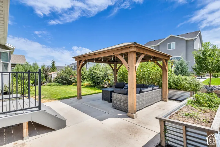 Expansive backyard patio featuring a wood gazebo, concrete hardscaping, and raised corrugated metal planters