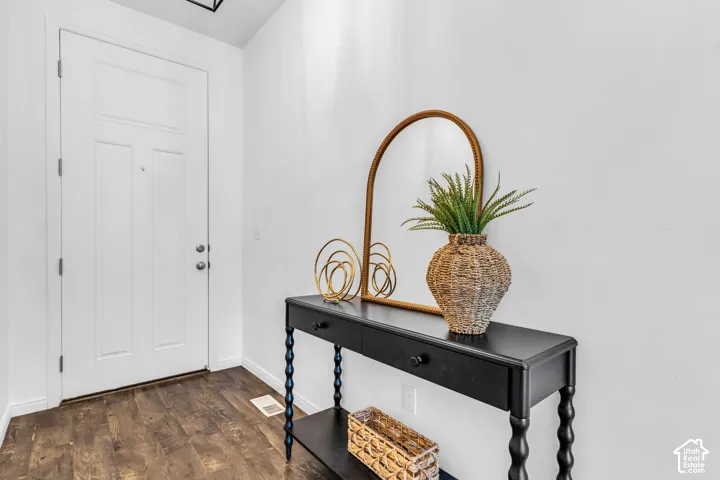 Inviting entry space featuring wood-finish flooring, a white paneled door, and bright white walls