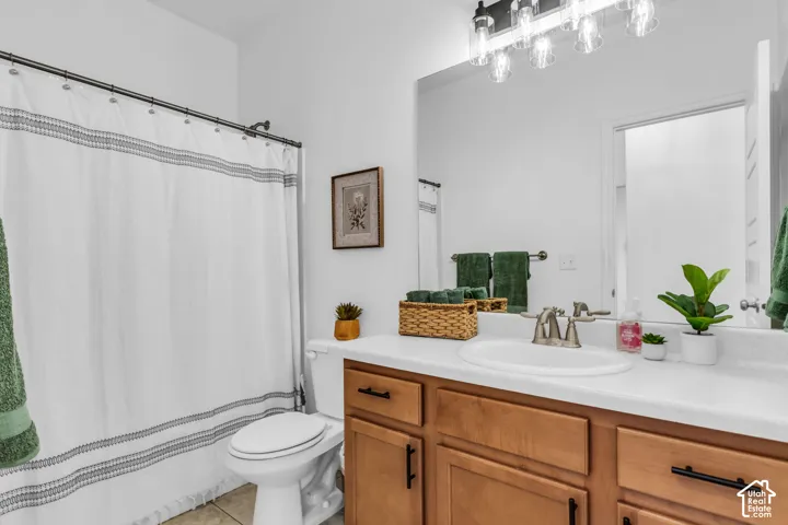 Bathroom vanity featuring a light wood-finish cabinet with black hardware, a white countertop, and an oval undermount sink with a brushed nickel faucet