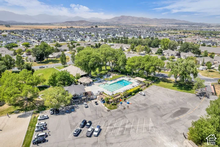 Expansive aerial view showcasing a large community swimming pool with multiple lanes, surrounded by mature trees and residential properties