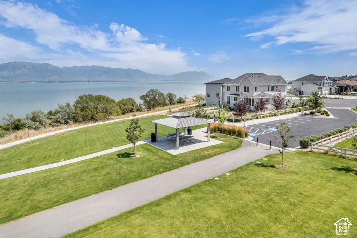 Expansive green space with a paved walking path, covered picnic area, and designated parking