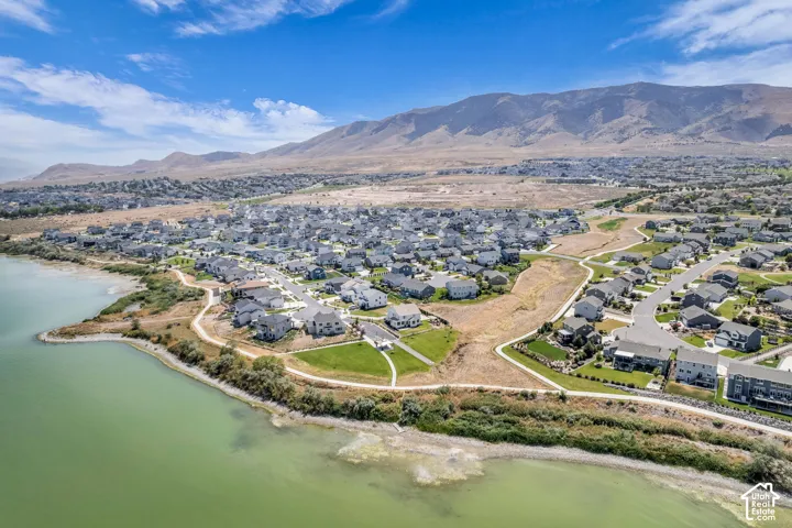 Aerial perspective of a developed residential community situated along a body of water, featuring a mountainous backdrop