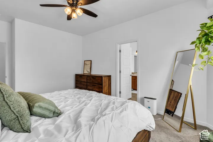Bedroom featuring an overhead ceiling fan with integrated lighting, neutral wall finishes, and carpet flooring
