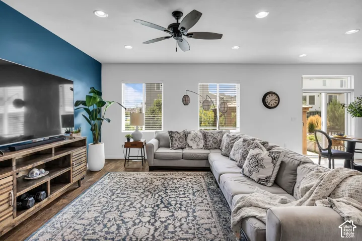 Spacious living area featuring a prominent accent wall, wood-finish flooring, recessed lighting, and a ceiling fan
