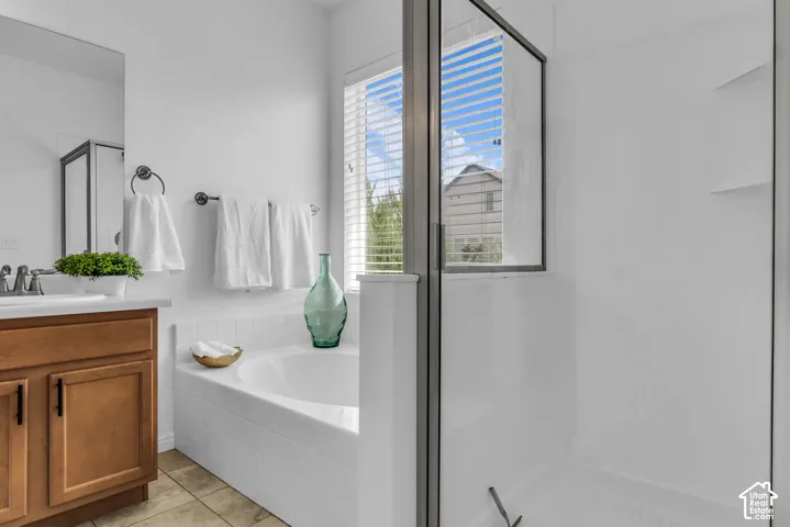 Bathroom featuring a built-in tub, a glass-enclosed shower with integrated shelving, and a vanity with wood-finish cabinetry and a white countertop