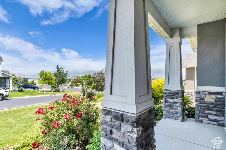 Front porch featuring stone-clad columns, a concrete slab, and a painted wood ceiling