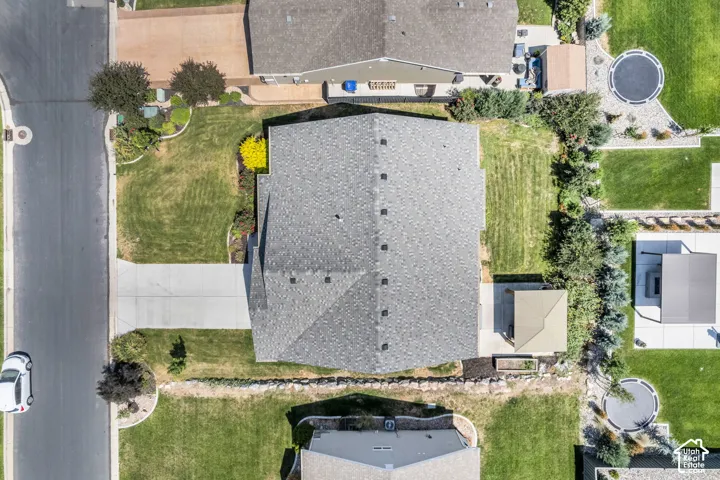 Aerial perspective showcasing the property's footprint with a gray shingle roof and an expansive concrete driveway