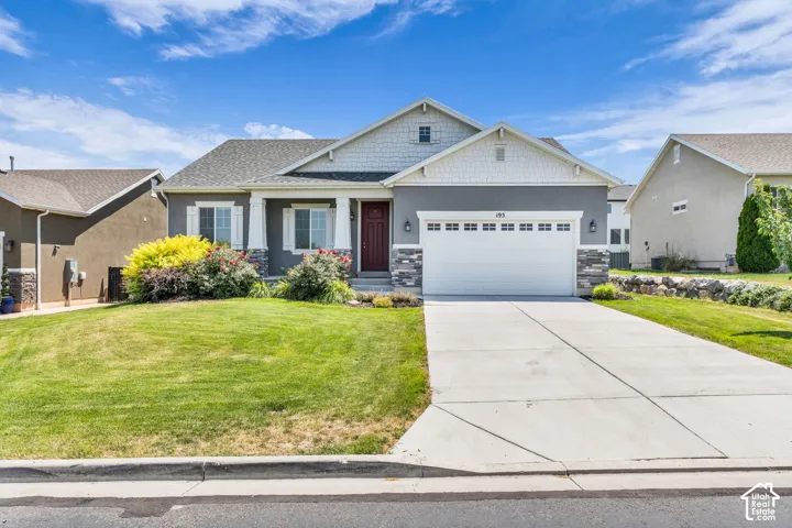 Ranch-style residence featuring a combination of gray stucco and white shake siding, a two-car garage, stone accents, a concrete driveway, and mature landscaping