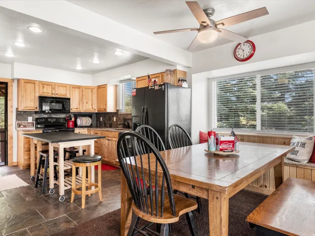Kitchen featuring wood cabinetry, black appliances, and a dark tile backsplash