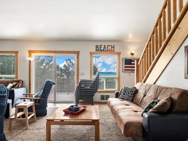 Living area featuring a natural wood staircase, light-colored walls, and carpeting
