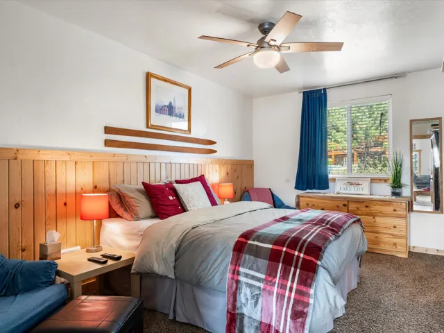 Bedroom featuring a natural wood panel accent wall, ceiling fan, and carpeted flooring