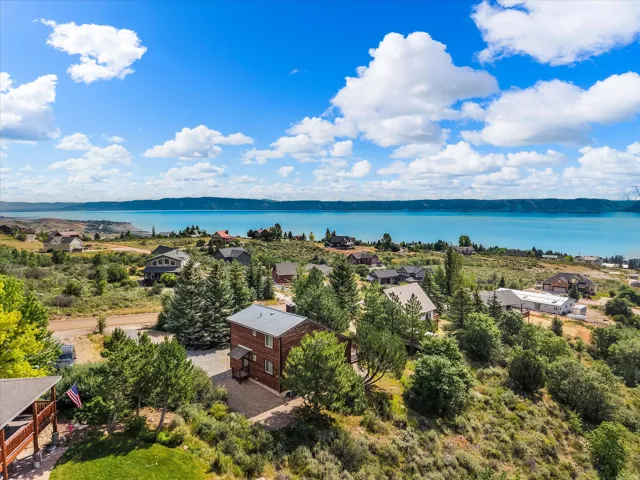 Elevated property featuring a two-story residence with a metal roof, surrounded by mature trees and natural landscaping
