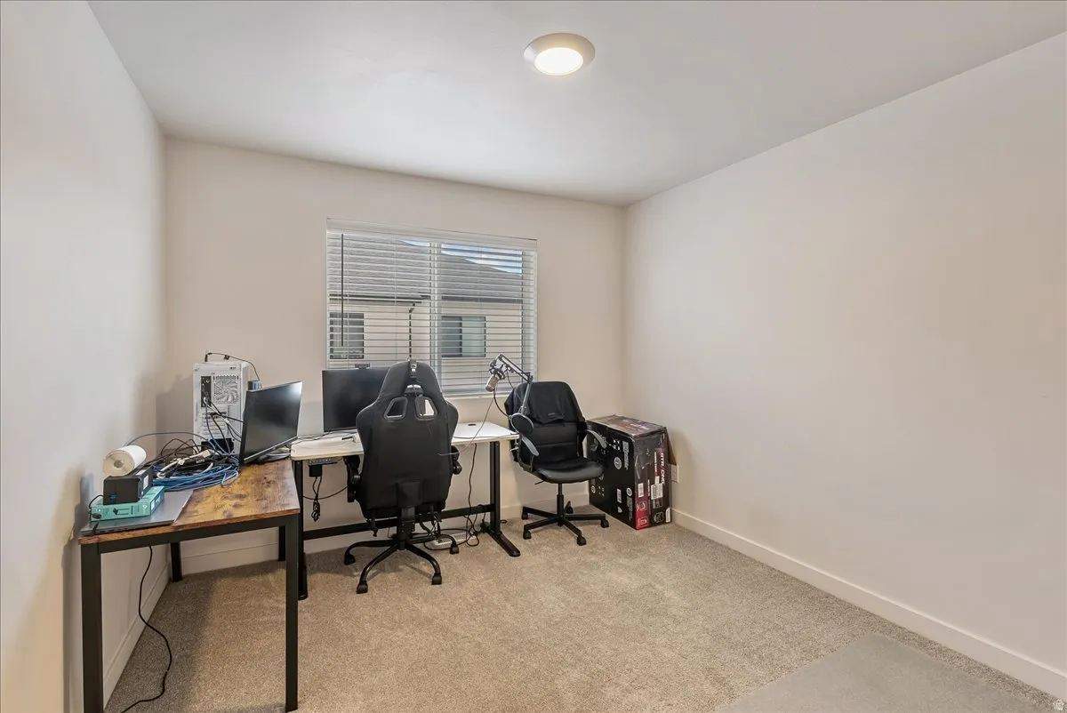 Carpeted room with a window featuring horizontal blinds