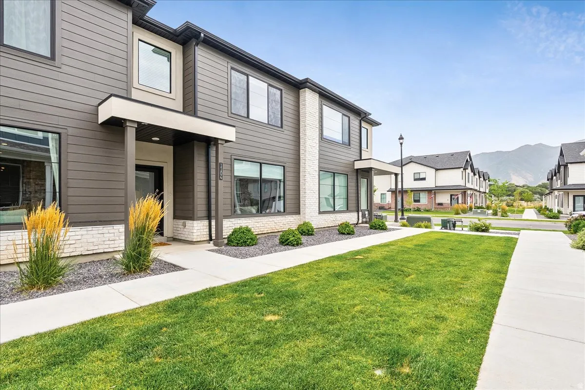 Modern multi-level residence featuring dark siding, white brick accents, and a covered entry