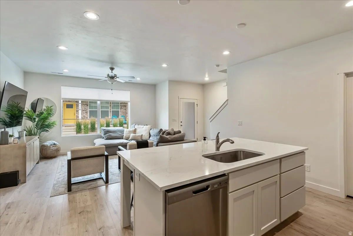 Contemporary open-concept living space featuring a kitchen island with an undermount stainless steel sink and integrated dishwasher