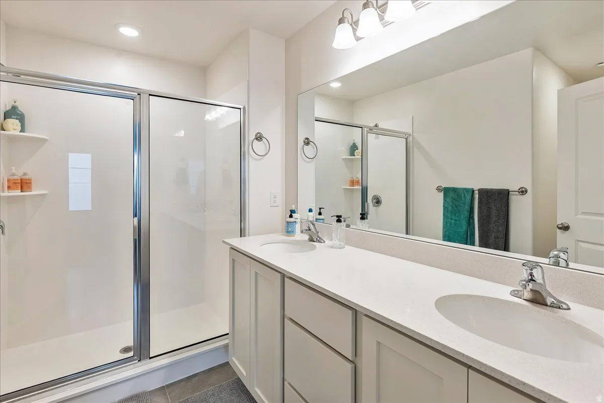 Full bathroom featuring a walk-in shower with clear glass enclosure, dual vanity with undermount sinks, and a full-width mirror