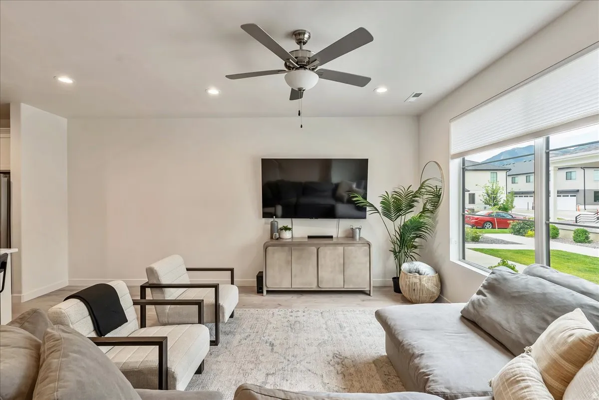 Spacious living area featuring a large picture window, recessed lighting, and a ceiling fan