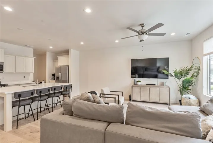 Open-concept living area featuring light wood-finish flooring, recessed lighting, and a contemporary ceiling fan
