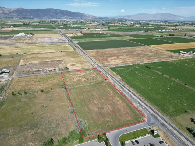 Expansive corner lot featuring open land, paved road frontage, and a mountainous backdrop. LOOKING WEST TO I15 ACCESS