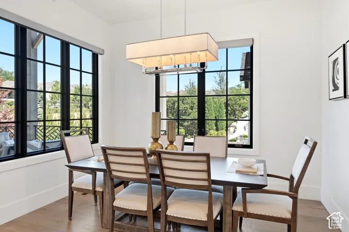 Dining area featuring large grid-pattern windows, a contemporary rectangular chandelier, and light wood-finish flooring