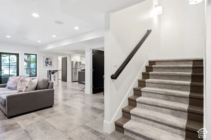 Carpeted staircase with dark wood-finish risers and handrail