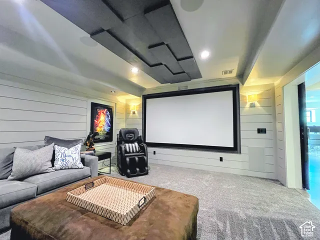 Dedicated media room featuring a large projection screen, shiplap wall accents, recessed lighting, wall-mounted sconces, and acoustic ceiling panels